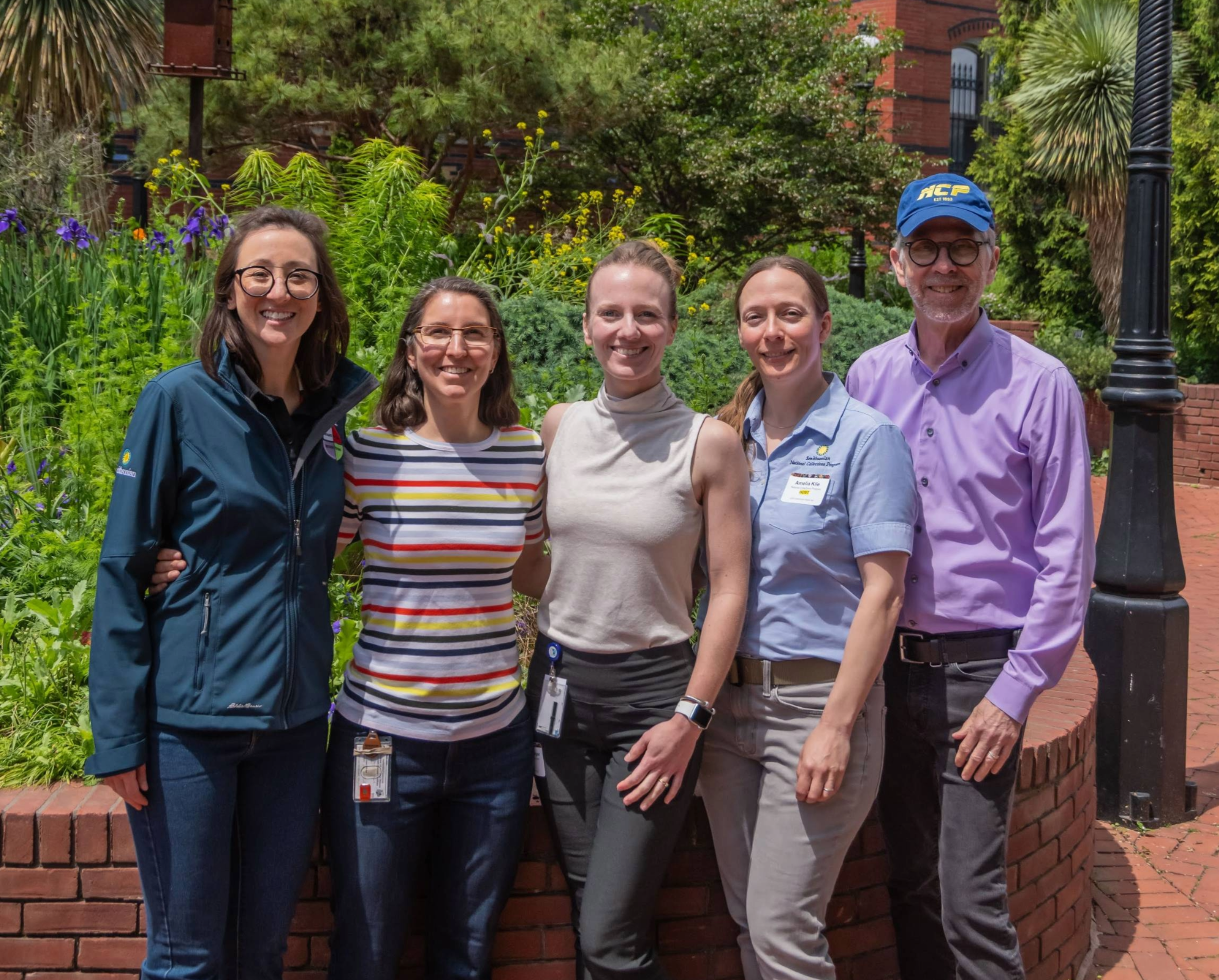 5 individuals standing together in front of spring greenery