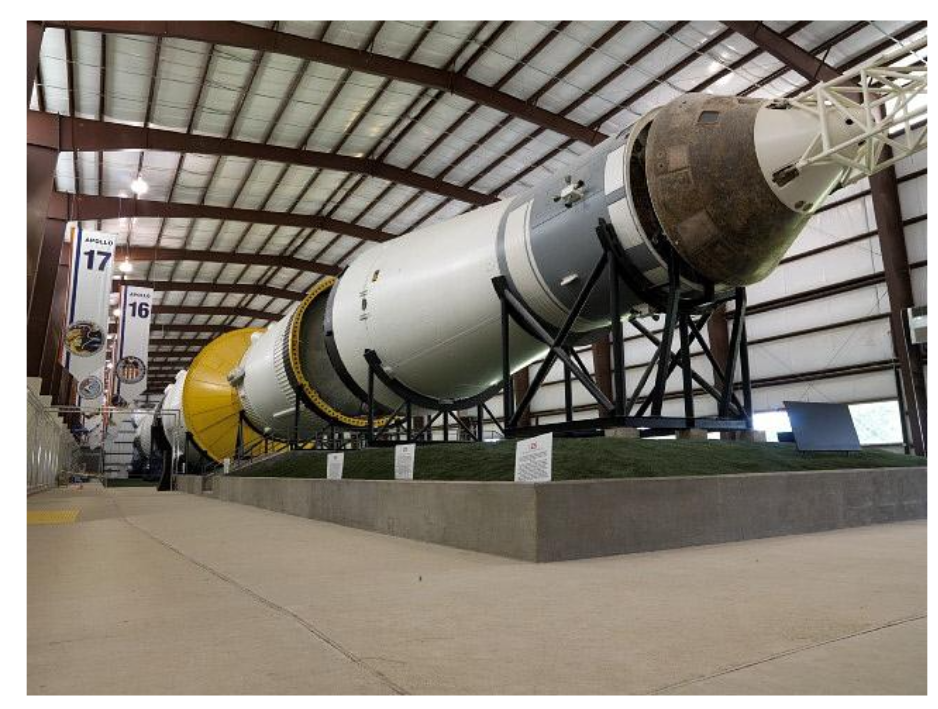 Photo of a large rocket with white and gray thin gauge aluminum exterior  laying horizontally on display